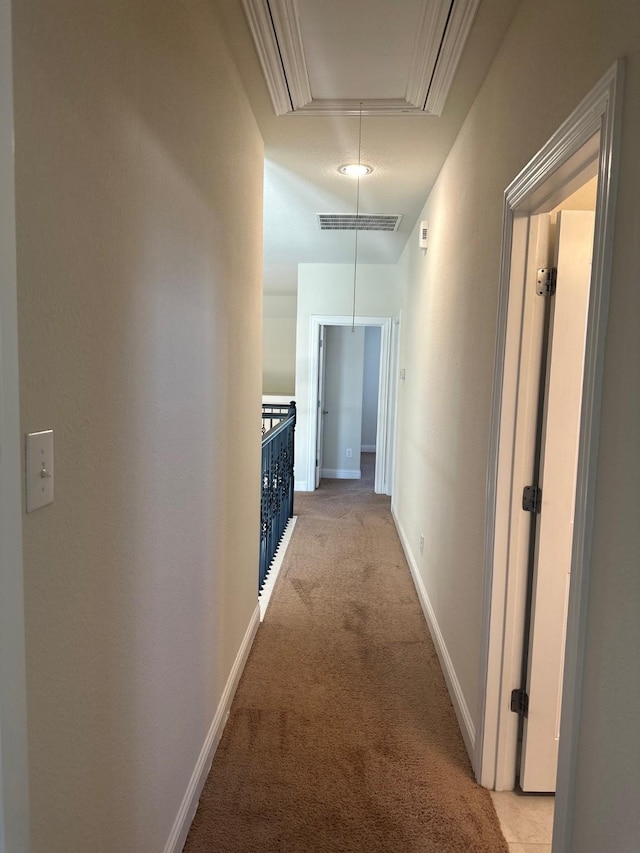 hallway featuring light carpet, attic access, visible vents, and baseboards