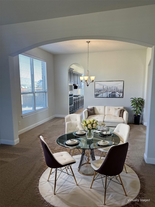 dining area featuring arched walkways, carpet, baseboards, and an inviting chandelier