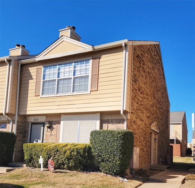 view of home's exterior with brick siding and a chimney