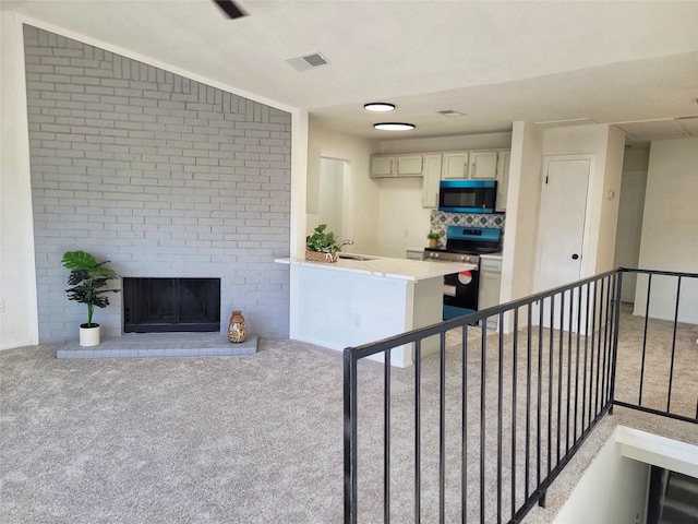 kitchen with light carpet, a fireplace, visible vents, and stainless steel range with electric cooktop