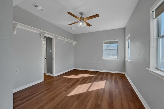 spare room with dark wood-style floors, visible vents, and baseboards