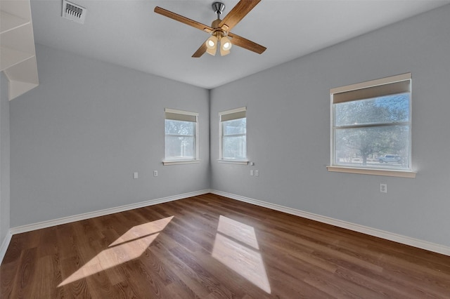 empty room with baseboards, visible vents, ceiling fan, and wood finished floors