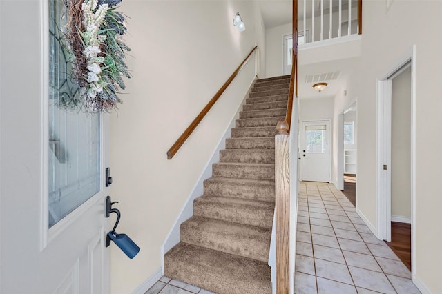 interior space featuring light tile patterned floors, stairs, visible vents, and baseboards