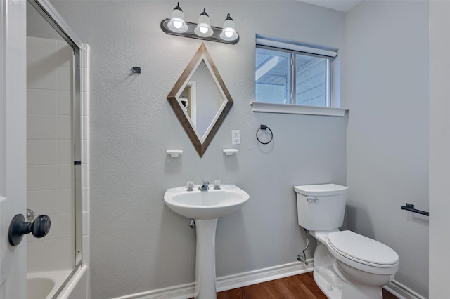 bathroom with shower / tub combination, wood finished floors, toilet, and baseboards