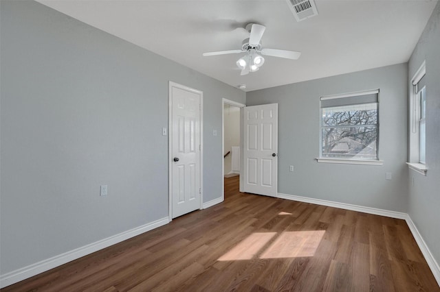 unfurnished bedroom with a ceiling fan, visible vents, baseboards, and wood finished floors