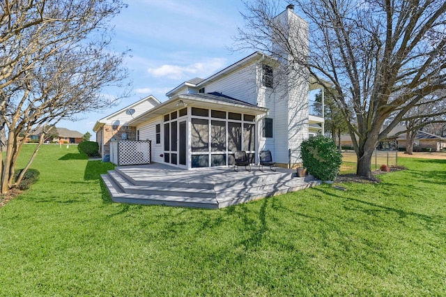 rear view of property featuring a sunroom, a yard, a chimney, and a wooden deck