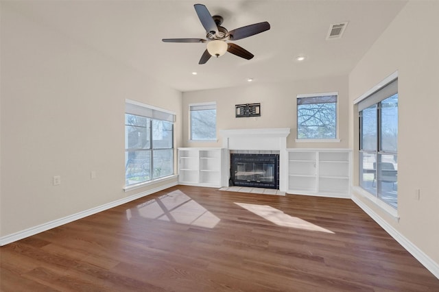 unfurnished living room featuring baseboards, visible vents, wood finished floors, and a tile fireplace