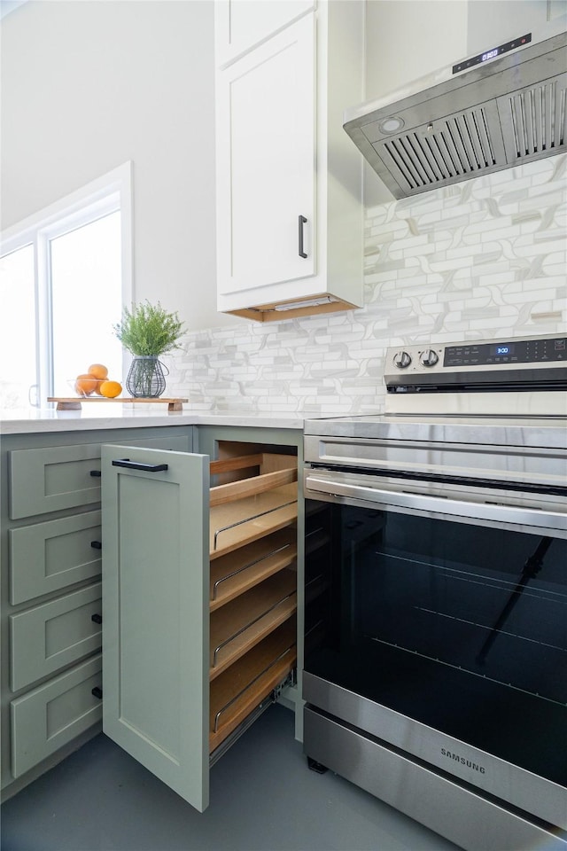 kitchen with electric range, exhaust hood, white cabinets, light countertops, and decorative backsplash