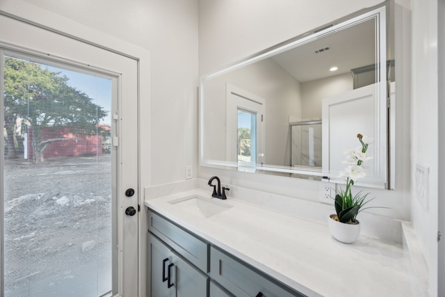 bathroom featuring a shower with shower door, vanity, and visible vents