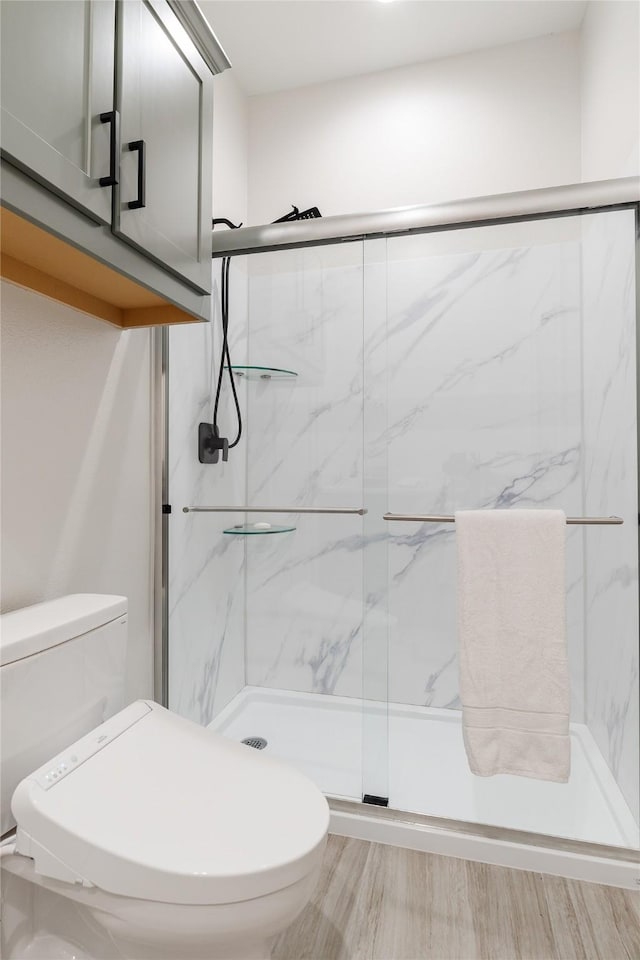 full bathroom featuring wood finished floors, a marble finish shower, and toilet