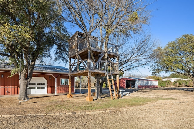 back of property with board and batten siding, metal roof, an attached garage, and a lawn