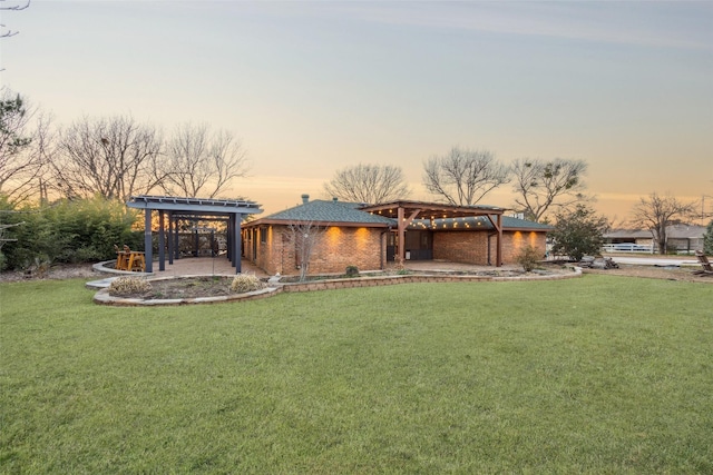 back of house at dusk with a lawn, a patio, a gazebo, a pergola, and brick siding