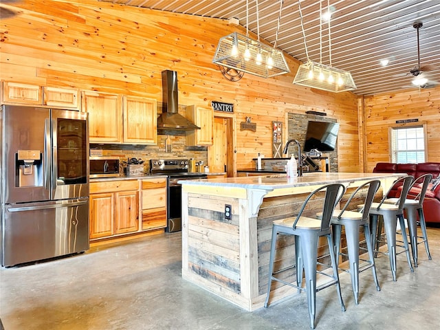 kitchen featuring wall chimney exhaust hood, open floor plan, stainless steel appliances, concrete flooring, and a sink