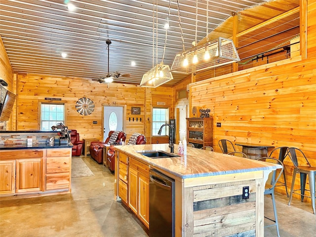 kitchen with dishwasher, wood walls, concrete floors, and a sink