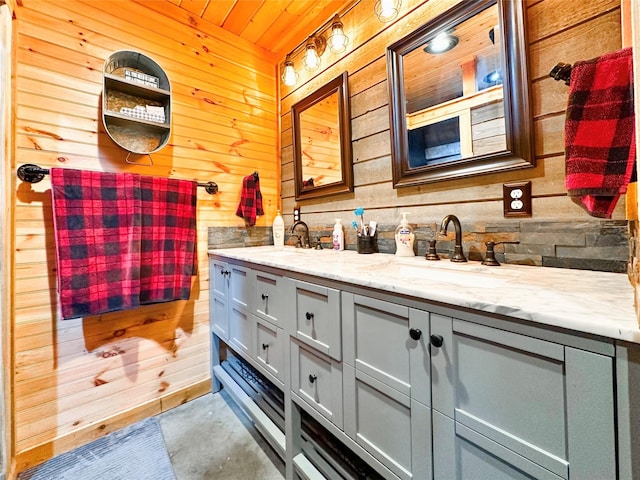 bathroom featuring wood walls and a sink