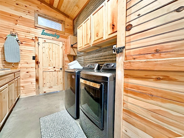 laundry area featuring cabinet space, wood ceiling, wooden walls, and washing machine and clothes dryer