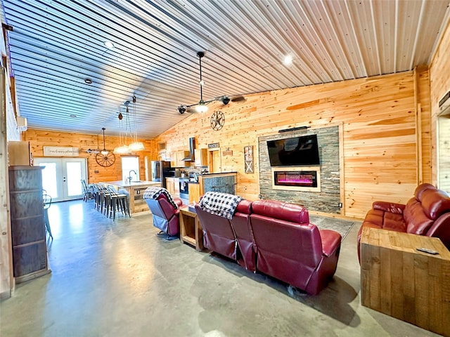 living room featuring wooden walls, wood ceiling, vaulted ceiling, concrete flooring, and french doors