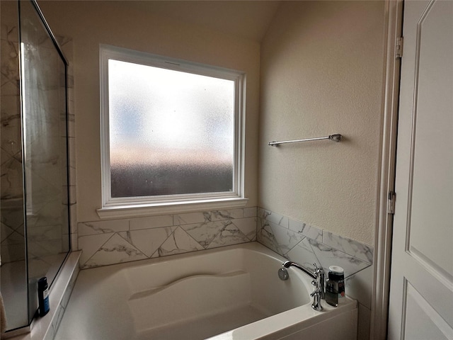 full bathroom featuring a garden tub, a shower, and a textured wall