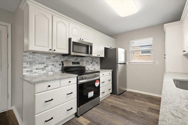 kitchen featuring white cabinets, appliances with stainless steel finishes, backsplash, light stone countertops, and dark wood finished floors