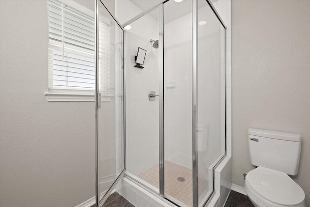 bathroom featuring baseboards, a shower stall, and toilet