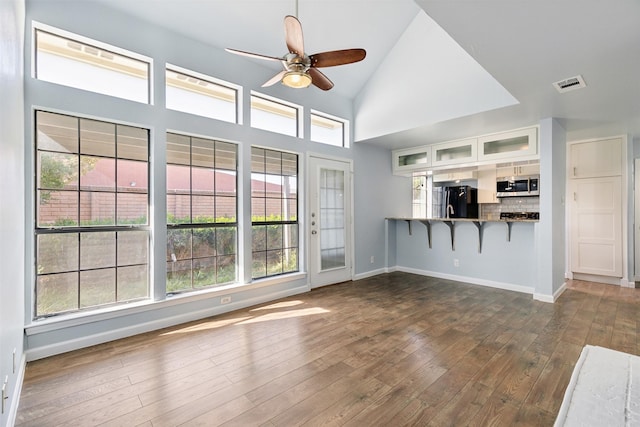 unfurnished living room with visible vents, dark wood-type flooring, baseboards, high vaulted ceiling, and a ceiling fan