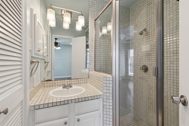full bathroom with vanity, a ceiling fan, and a shower stall