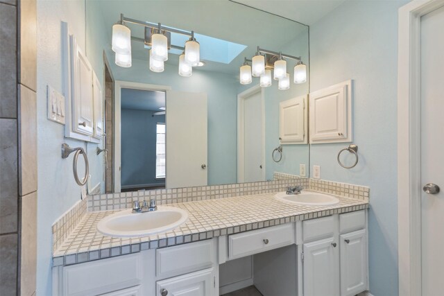 bathroom with double vanity, a sink, and a skylight