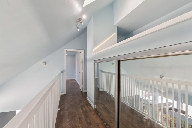 hallway featuring baseboards, lofted ceiling, and wood finished floors