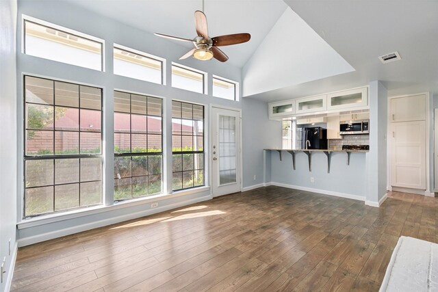 unfurnished living room featuring high vaulted ceiling, dark wood-type flooring, baseboards, visible vents, and a ceiling fan