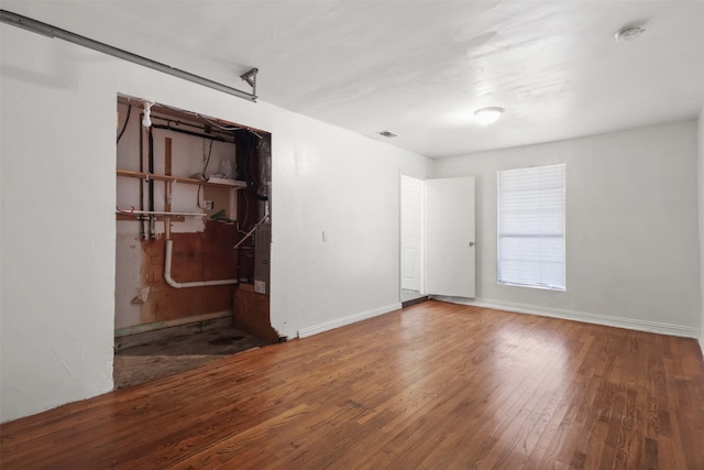 unfurnished room with visible vents, baseboards, and wood finished floors