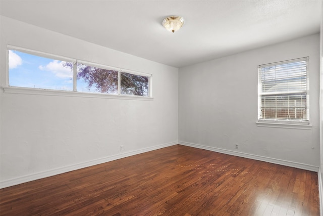 spare room with wood-type flooring and baseboards