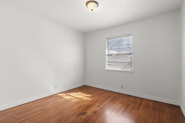 spare room featuring hardwood / wood-style floors and baseboards