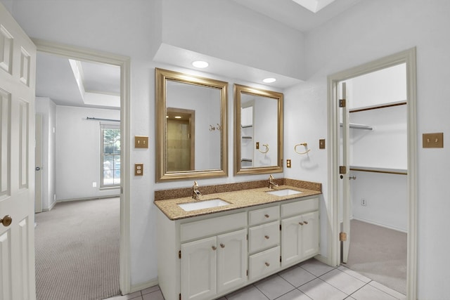 full bathroom with double vanity, tile patterned flooring, a sink, and baseboards