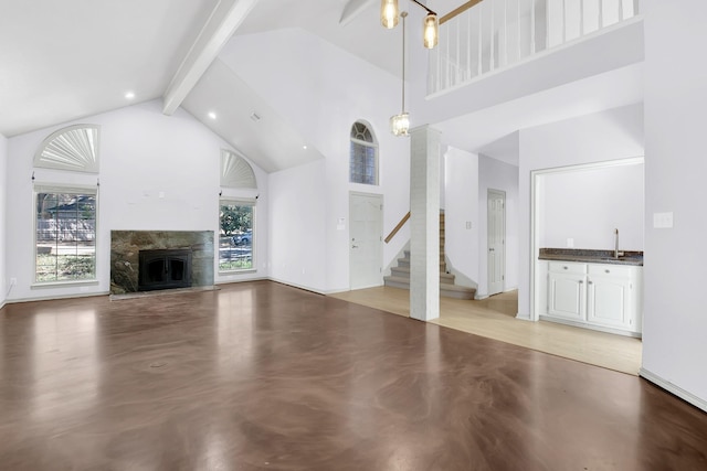 unfurnished living room with high vaulted ceiling, a fireplace, finished concrete flooring, stairway, and beamed ceiling