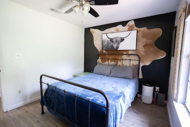 bedroom featuring a ceiling fan, baseboards, visible vents, and wood finished floors