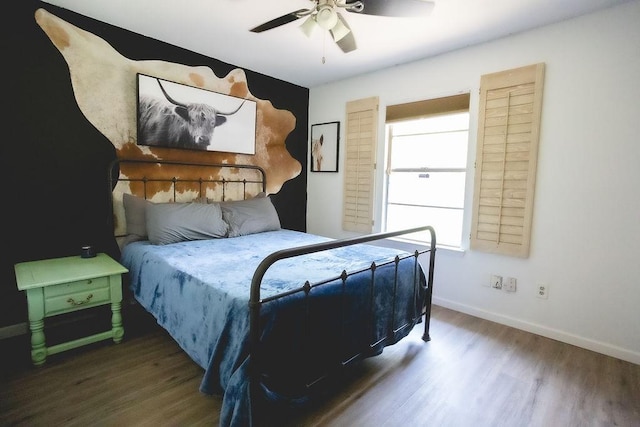 bedroom with a ceiling fan, baseboards, and wood finished floors