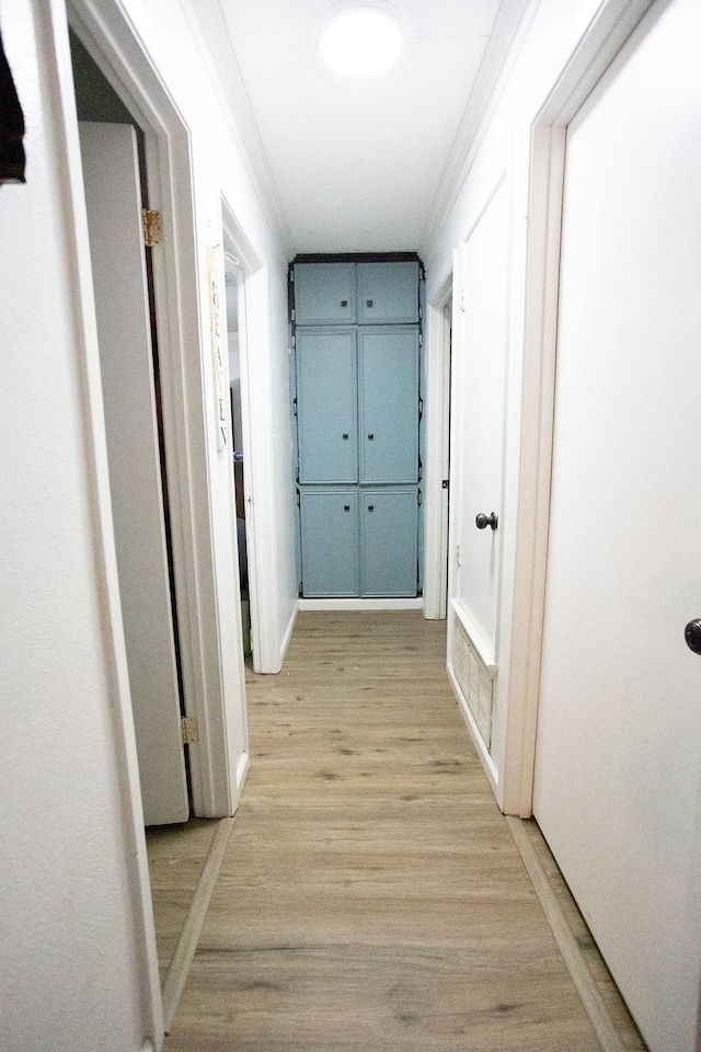 hallway with light wood-style flooring and ornamental molding