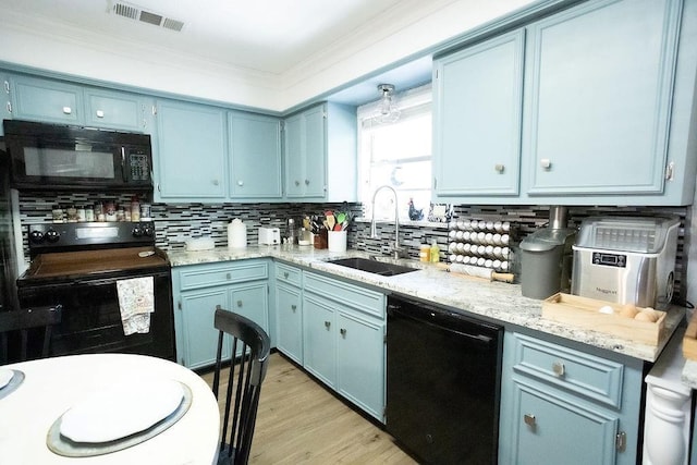 kitchen with black appliances, ornamental molding, blue cabinetry, and a sink