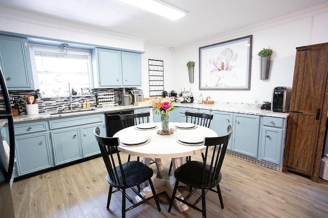 kitchen featuring blue cabinets, a sink, ornamental molding, light wood-type flooring, and backsplash