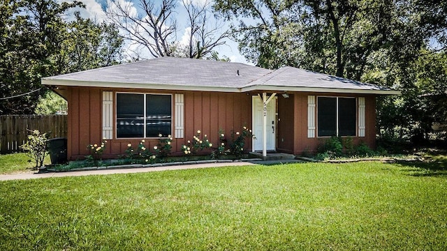 view of front facade with board and batten siding, a front yard, and fence