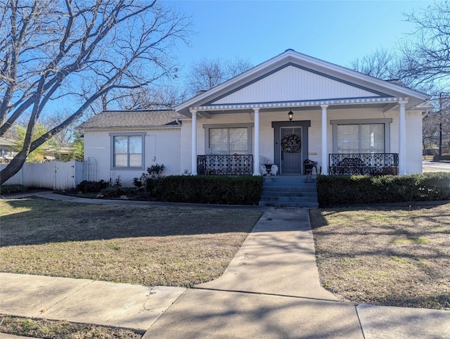 view of front of home with brick siding, a porch, fence, and a front yard