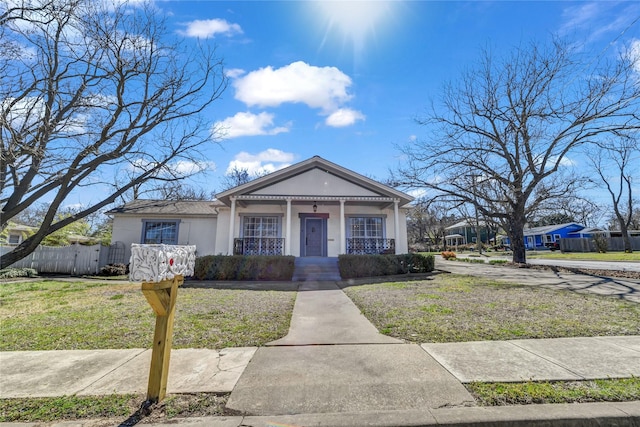 view of front facade with stucco siding, a porch, a front lawn, and fence