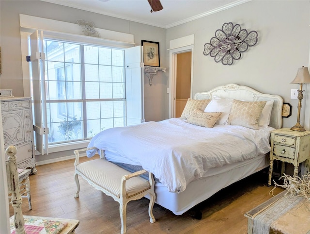 bedroom with ceiling fan, crown molding, baseboards, and wood finished floors