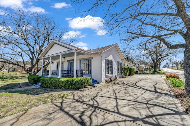 view of front of house featuring a porch, stucco siding, and aphalt driveway