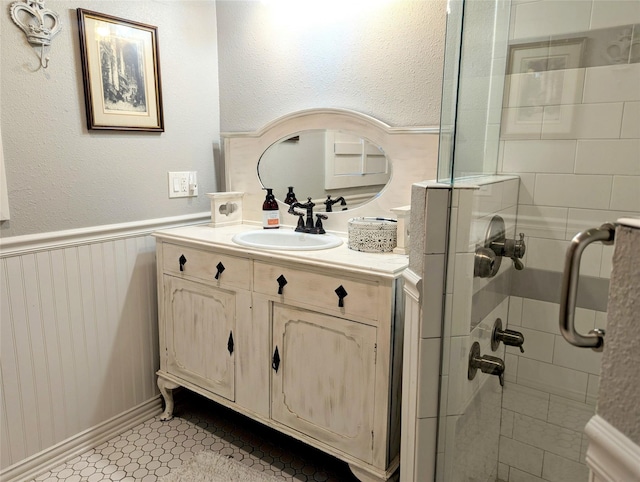 full bath featuring wainscoting, a shower stall, and vanity