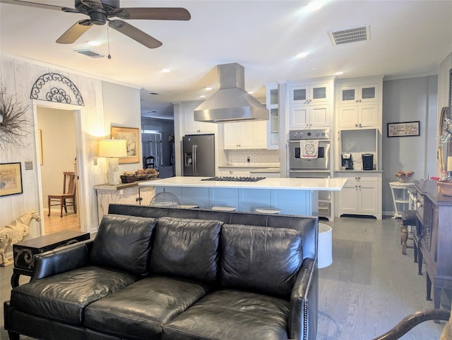 kitchen featuring visible vents, island range hood, white cabinets, glass insert cabinets, and appliances with stainless steel finishes