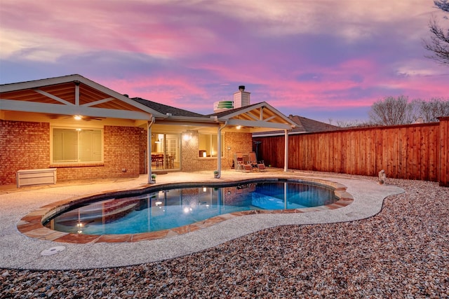 pool at dusk featuring a patio area, a fenced backyard, and a fenced in pool