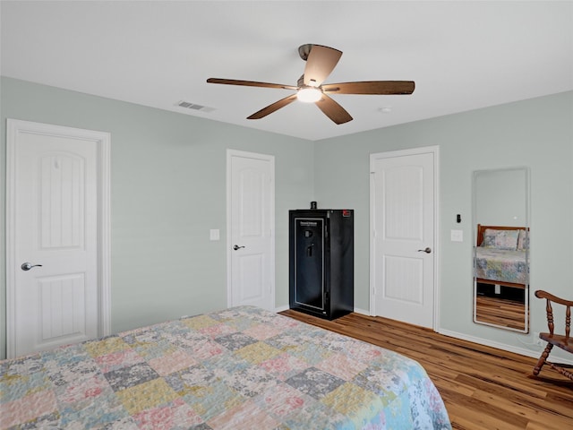 bedroom featuring visible vents, ceiling fan, baseboards, and wood finished floors