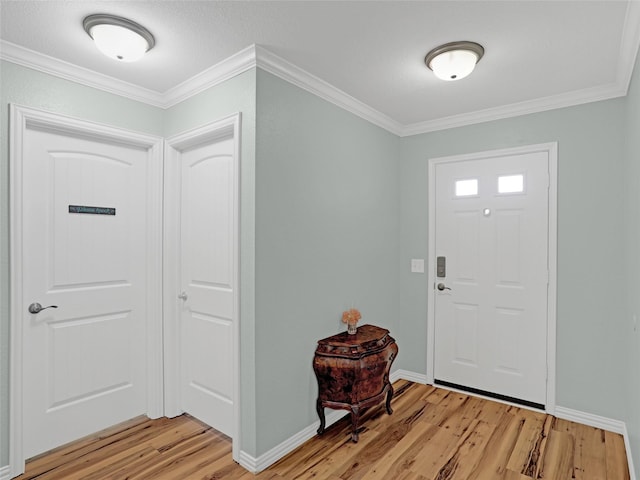 foyer entrance with light wood finished floors, baseboards, and crown molding