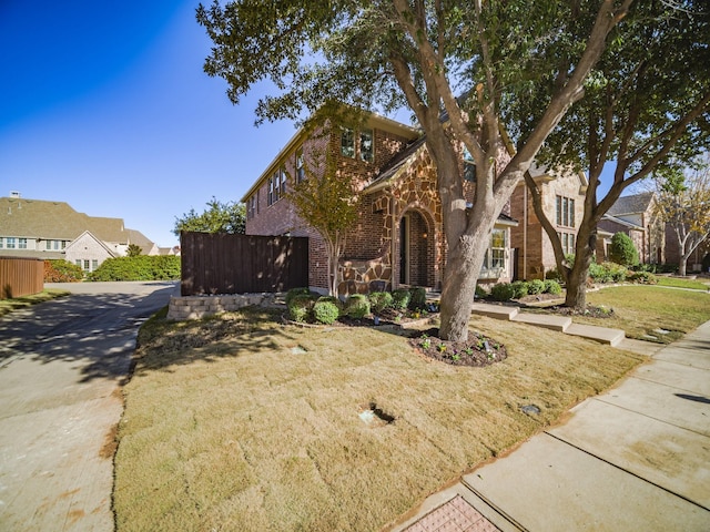 view of front of property with stone siding, brick siding, and fence